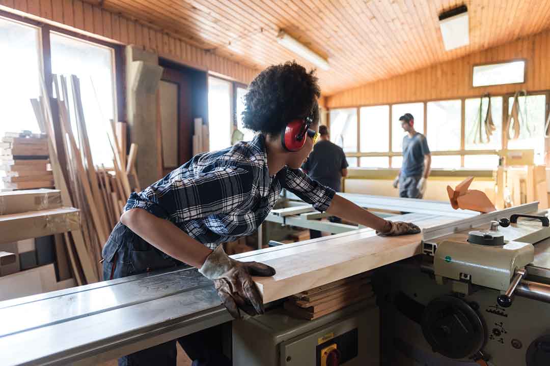 A female cutting wood on a table saw